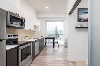 a kitchen with stainless steel appliances and a door to a balcony